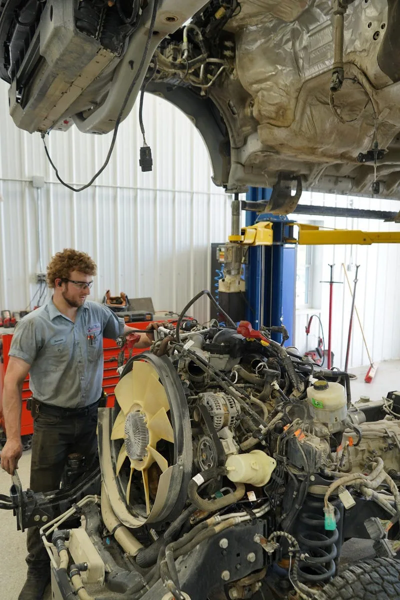 Auto Tech technician removing an engine from a truck on the lift in Versailles, MO