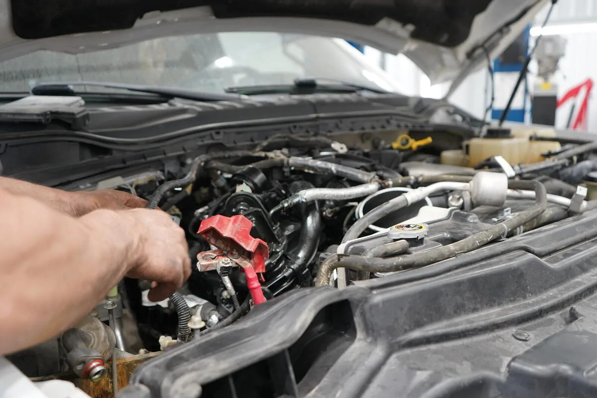 Technician hands working on engine components under the hood